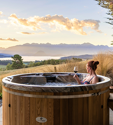 Dreamaroo Luxury, Barefoot Luxury New Zealand, Woman In Hot Tub Holding Glass of Wine Looking Out At View of Mountains Image