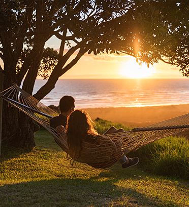 Dreamaroo Luxury, Honeymoon & Beautiful Islands New Zealand, Man and Woman Couple On Hammock Watching The Ocean Sunset View Image