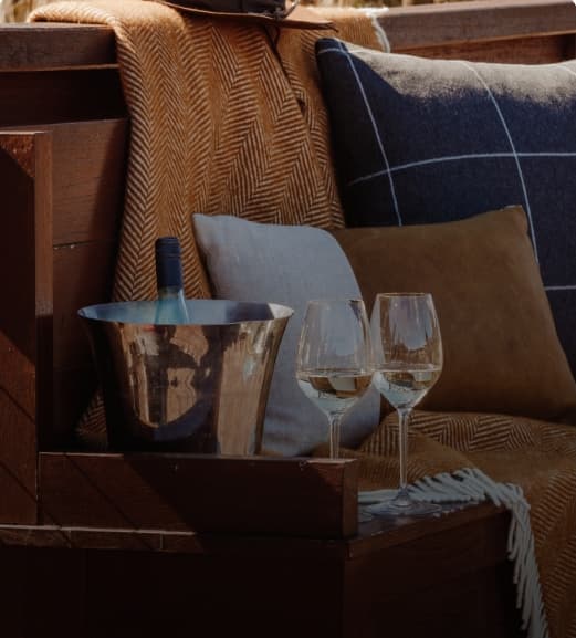 Dreamaroo Luxury, Two Glasses of Wine Next To A Bottle in a Bucket On a Bench With Blankets & Pillows Image