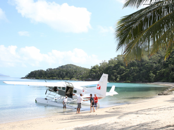Dreamaroo Luxury, White Plane on Beach Shore, Four People Nearby Image