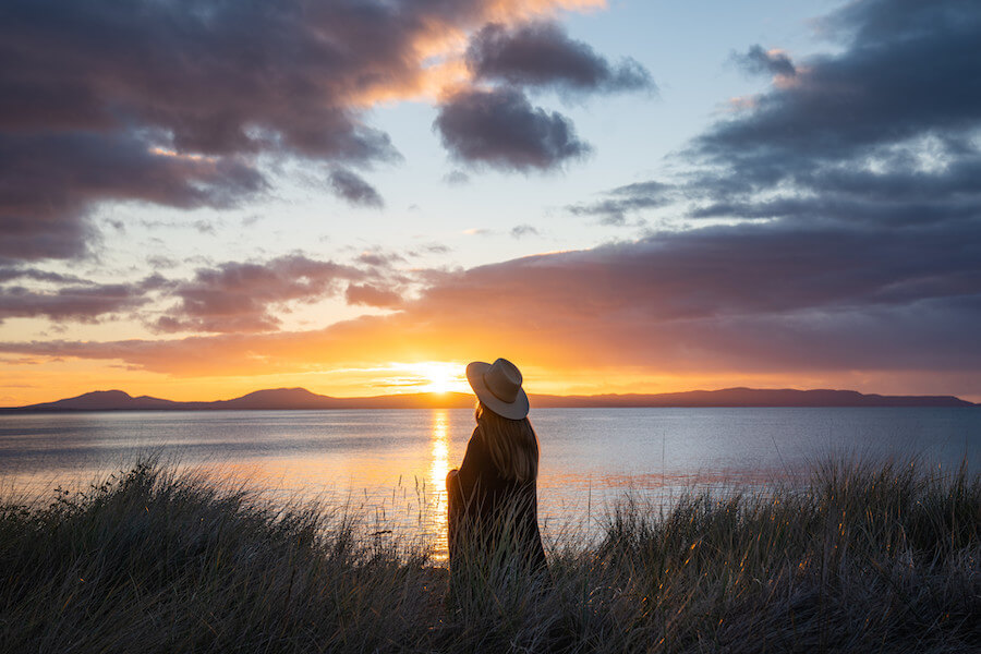 Dreamaroo Luxury, Back View of Woman With Hat and Shawl, Field & Sunset View of Ocean Image